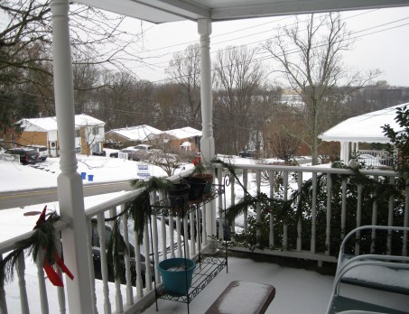 A porch overlooking a snow-covered neighborhood